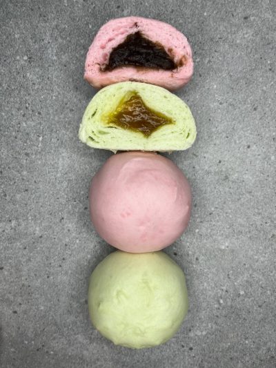 Pandangan atas pau mini berwarna hijau dan merah jambu, dua daripadanya dibelah dua menunjukkan inti kaya dan inti kacang merah. Disusun secara selang seli.